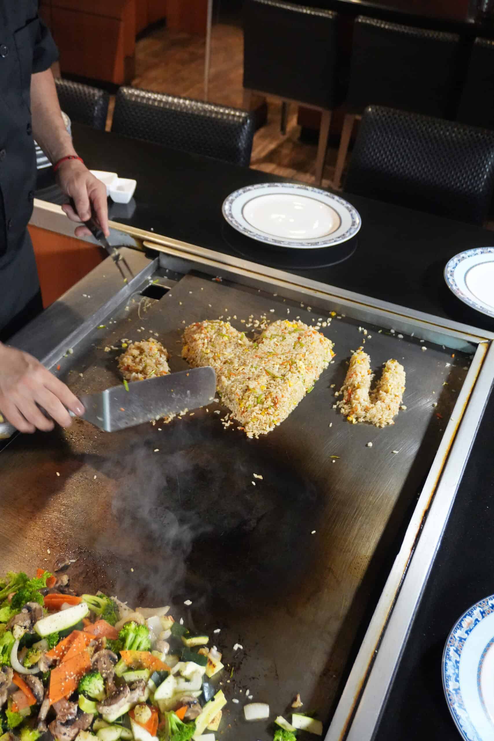 Chef preparing teppanyaki with vegetables and breaded meat in Osaka restaurant.